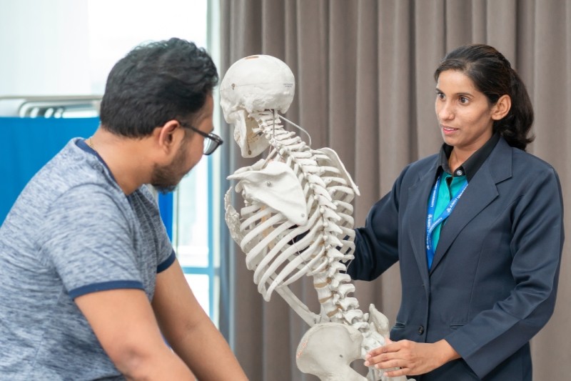 a doctor holding human skeleton to explain