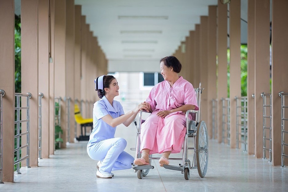 a nurse is smiling to female wheelchair patient