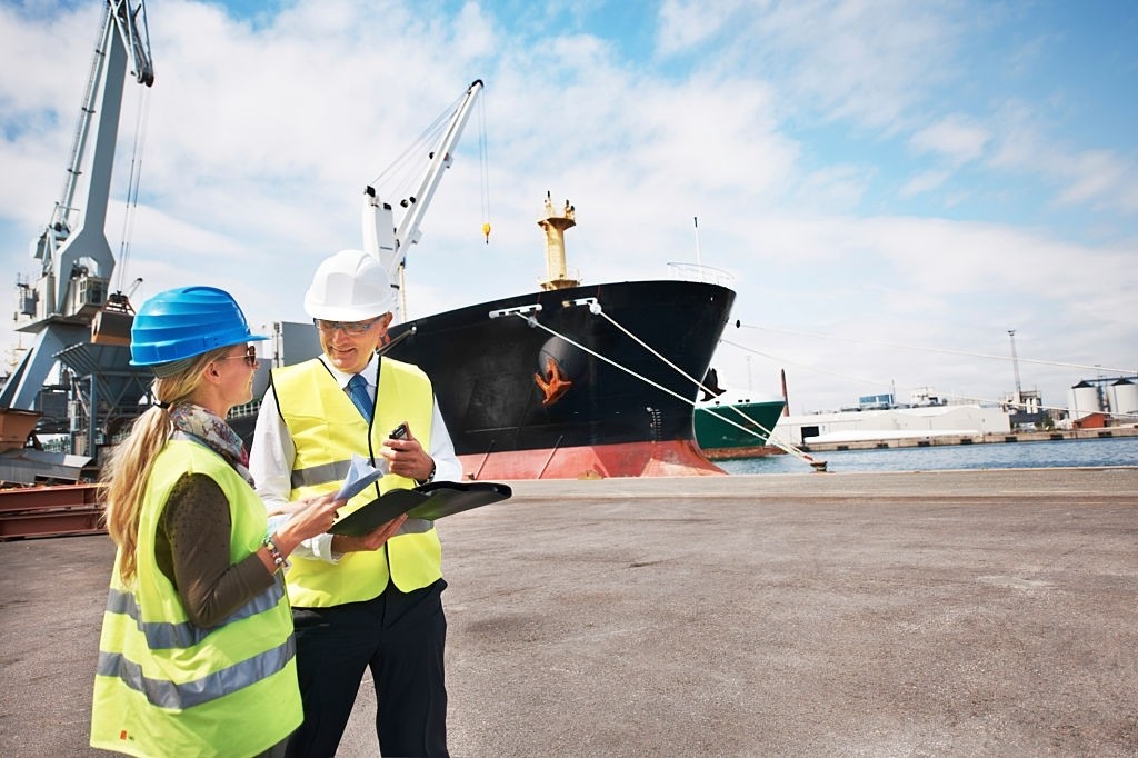 Two dock workers holding paperwork while standing in the shipyard