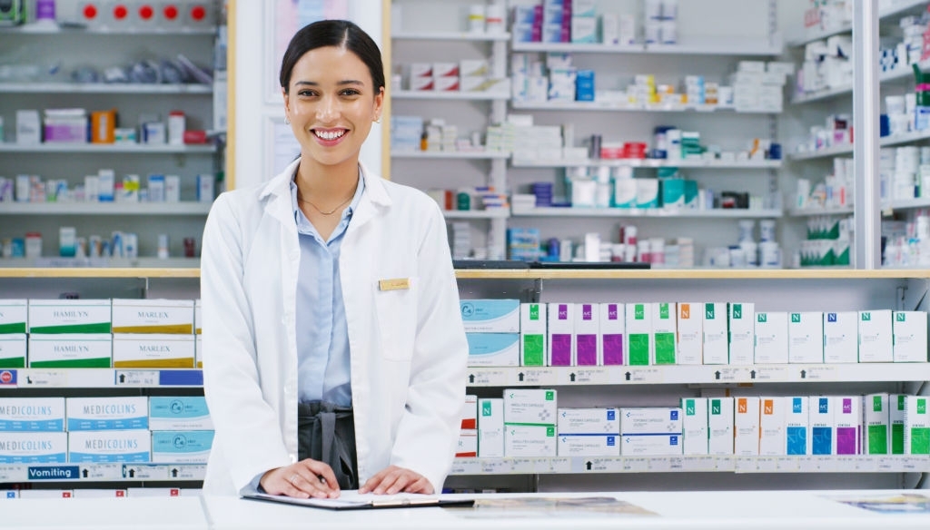 Portrait of a young pharmacist writing notes while working in a chemist