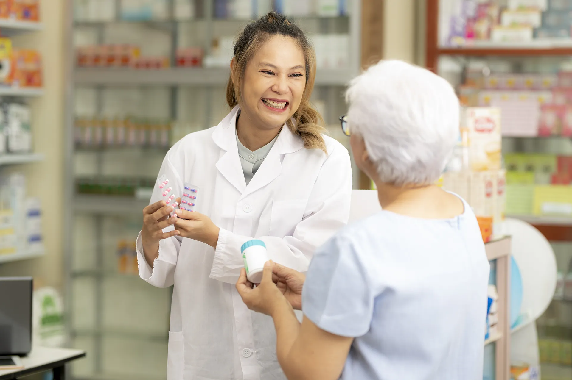 asian female pharmacist gives indian elderly woman