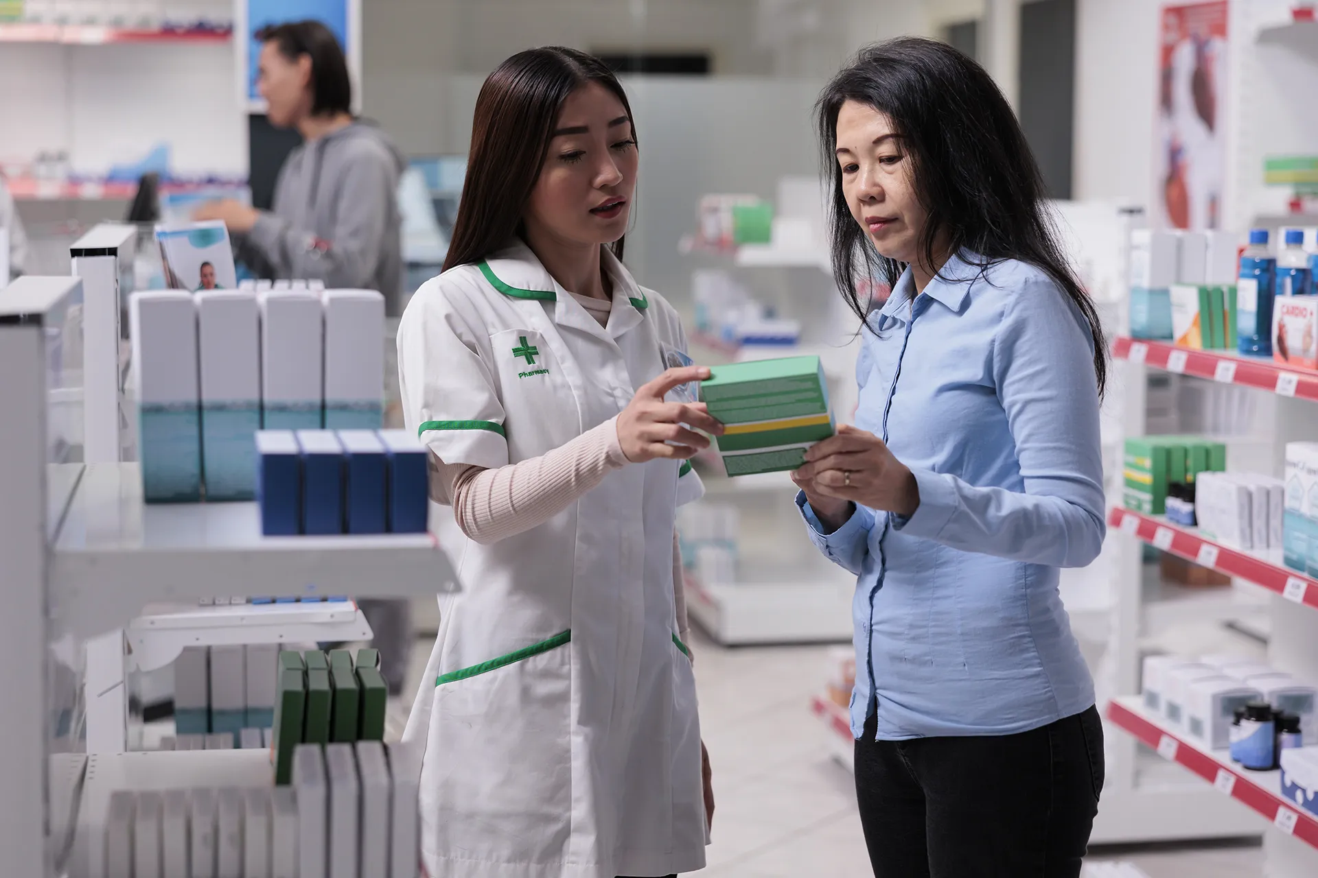 asian pharmacist explaining boxes of pills